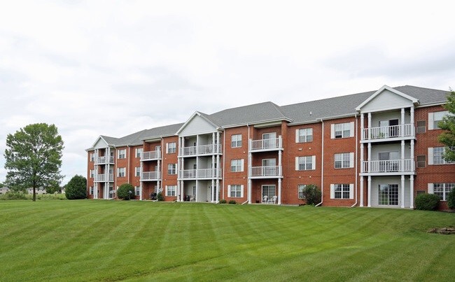 A large red brick apartment building with a green lawn in front.